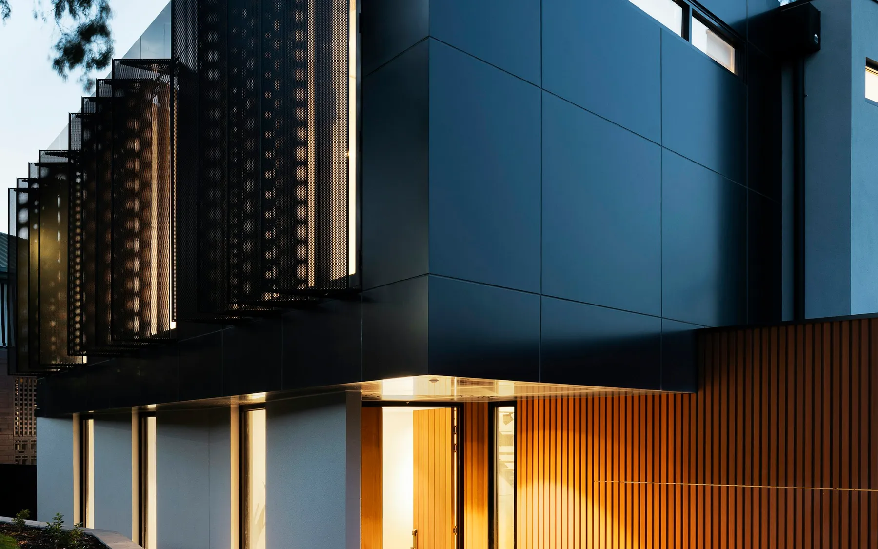 Casa de concreto y madera al atardecer, rodeada de árboles