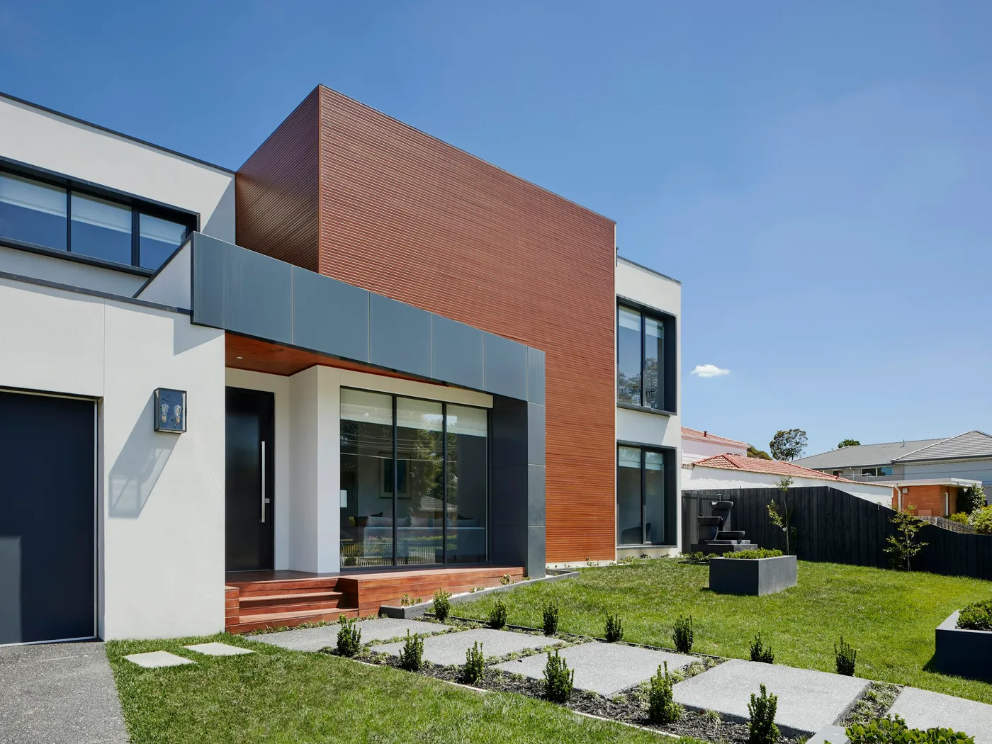 Townhouse de madera y muros blancos con jardín al frente